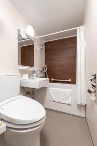 La salle de bains blanche est pourvue de toilettes et d'un lavabo. dans l'établissement Hiroshima Intelligent Hotel Stadium Mae, à Hiroshima