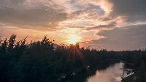 a sunset over a river with the sun in the sky at Seava Ho Tram Beach Resort in Ho Coc