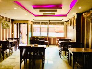 un restaurante con mesas, sillas y luces púrpuras en Hotel ACE, en Katmandú