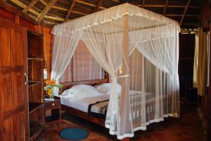 a canopy bed with white curtains in a bedroom at Galawatta Beach Resort in Unawatuna