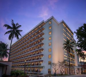 a large white building with palm trees in front of it at Sokha Beach Resort in Sihanoukville