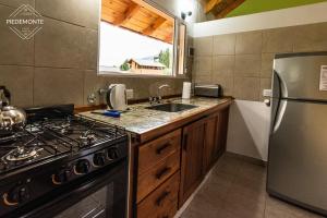 a kitchen with a stove and a stainless steel refrigerator at Cabaña Piedemonte in Lago Puelo