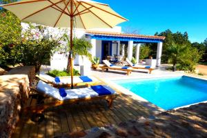 een zwembad met stoelen en een parasol naast een huis bij Finca Can Carlets in Cala Saona