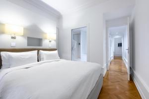 a white bedroom with a large bed and a hallway at Swiss Luxury Apartments in Geneva