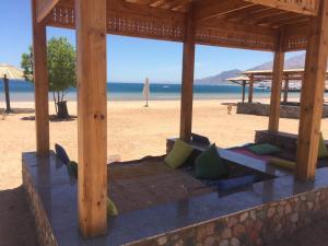 a wooden pavilion on a beach with the ocean at Deluxe Seahorse Apartment - Lagoon Villa in Dahab