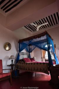sypialnia z łóżkiem z niebieskim baldachimem w obiekcie Zanzibar Palace Hotel w mieście Zanzibar