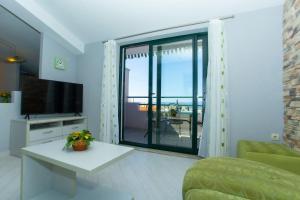 a living room with a tv and a large window at Apartments Loncar in Tučepi