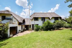 a large white house with a thatched roof and a yard at 41 Ridge- self catering cottages in Midrand