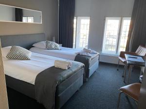 a hotel room with two beds and two windows at Hotel en Grand Café De Pauw in Roermond