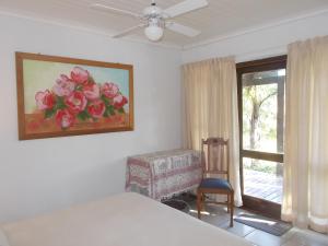 een slaapkamer met een bed en een raam met een schilderij van bloemen bij Erf 473 Fisherhaven in Fisherhaven