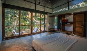 a bedroom with a large bed and large windows at Sati Villa Kandy Sri Lanka in Kandy