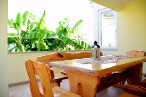 une table et des chaises en bois avec une fenêtre et des plantes dans l'établissement Villa Danny ****, à Dobropoljana