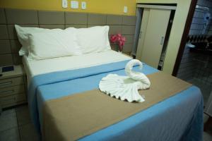 Hotel Litoral Sul في كوروريبي: بجعة بيضاء تجلس على سرير في غرفة النوم
