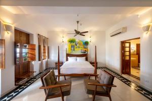 a bedroom with a bed and two chairs at Grand Hotel D'Europe in Pondicherry