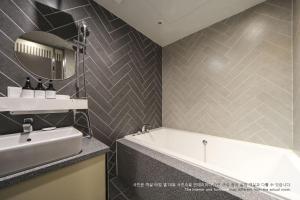 釜山にあるル イデア ホテル プサン ステーションのバスルーム(バスタブ、シンク、鏡付)