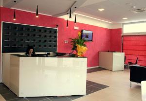 a woman sitting at a counter in a red wall at Silver Residence Hotel in Bagnolo in Piano