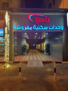 un bâtiment avec un panneau de néon sur son côté dans l'établissement Yahalla Hotel Units, à Djeddah