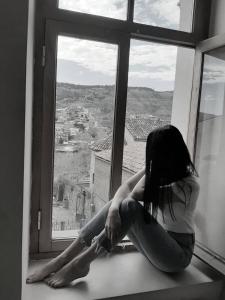 Kobieta siedząca na parapecie i patrząca na zewnątrz w obiekcie Hotel Vita w mieście Tbilisi City
