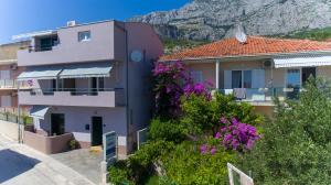 a building with purple flowers in front of a mountain at Apartments Loncar in Tučepi