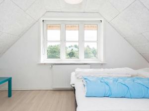 a white bedroom with a bed and a window at 21 person holiday home in Bl vand in Blåvand
