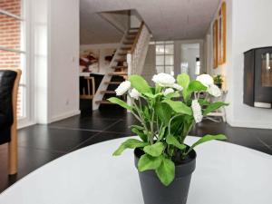 a black vase with white flowers sitting on a table at 21 person holiday home in Bl vand in Blåvand