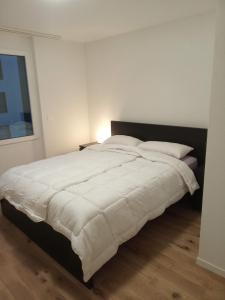 1 dormitorio con 1 cama grande con mantas y almohadas blancas en Appartement Daria Cossonay, en Cossonay