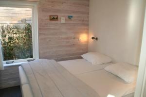 een bed met 2 kussens in een kamer met een raam bij Rekerlanden 154 in Schoorldam