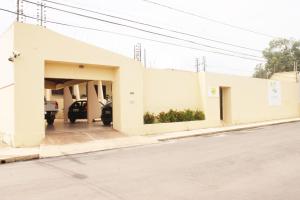 a white building with a car parked in the garage at Hotel Pousada Calhau in São Luís