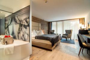 萨斯费Walliserhof Grand-Hotel & Spa Relais & Châteaux的酒店客房配有一张床和一张书桌,客房则配有桌子