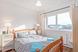1 dormitorio con cama y ventana en Trearddur Bay - Home with a view and Hot Tub - Sleeps 10, en Trearddur