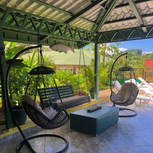 eine Terrasse mit Schaukeln, einer Bank und einem Tisch in der Unterkunft La Terraza Verde in Drake