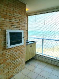 um quarto com uma parede de tijolos com uma televisão em Apartamento para relaxar de frente a praia na Praia Grande
