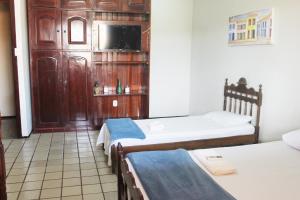 a room with two beds and a tv on a wall at Hotel Pousada Calhau in São Luís