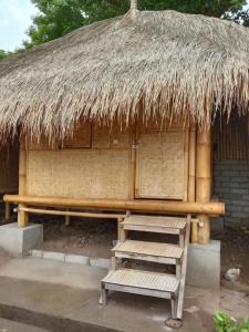 a hut with a bench and a straw roof at Gili Kampoeng in Gili Trawangan