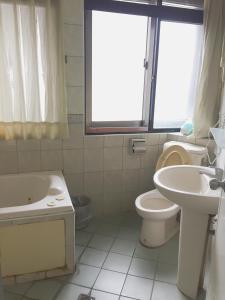 a bathroom with a toilet and a sink and a tub at Xiang Dou Hotel in Jiaoxi
