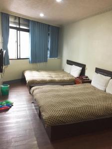 a hotel room with three beds and a window at Xiang Dou Hotel in Jiaoxi