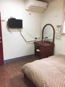 1 dormitorio con cama, escritorio y espejo en Xiang Dou Hotel, en Jiaoxi