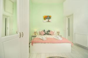 a white bedroom with a bed with pink sheets at Eco Studio in Braşov