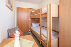 a room with two bunk beds and a table at Am Weststrand Apartmenthaus Waldeck in Kühlungsborn