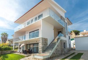 una grande casa bianca con finestre in vetro e scale di Casa em Cascais a Cascais