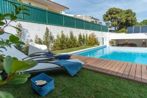 a backyard with a swimming pool with a deck and a chair at Casa em Cascais in Cascais