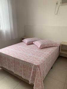 Una cama rosa con dos almohadas encima. en Apartamento novo Próximo ao Parque Beto carreiro, en Penha
