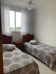 1 dormitorio con 2 camas y ventana en Apartamento novo Próximo ao Parque Beto carreiro, en Penha