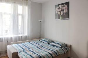 a bedroom with a bed with a blanket and a window at Riga Central Park Apartment in Riga