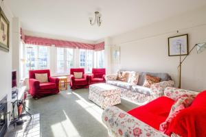 a living room with red chairs and couches at Lake Cottage in Thorpeness