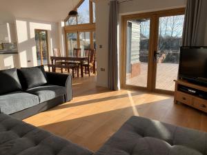 Una sala de estar con un sofá y un televisor. en Chestnut-Lodge is rural, secluded, private with Hot Tub, en Maidstone