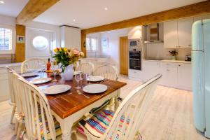 a kitchen with a wooden table with chairs and a refrigerator at Meare House in Thorpeness