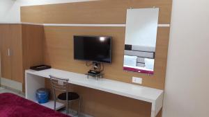 a room with a desk with a television on it at Hotel Zenith in Surat