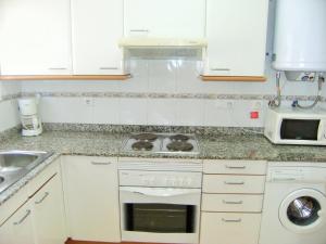 a white kitchen with a stove and a microwave at TARRACO 20 (BOLLERIA) in L'Estartit +4 photos