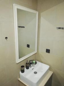 een badkamer met een witte wastafel en een spiegel bij Apartman Adelfes P16, Milmari Resort in Kopaonik